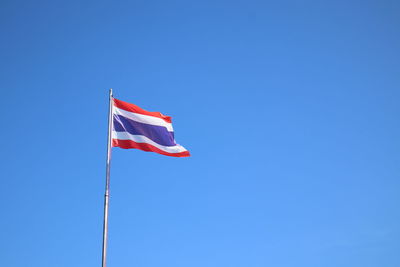 Low angle view of flag flags against clear blue sky