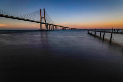 Bridge over calm sea at sunset