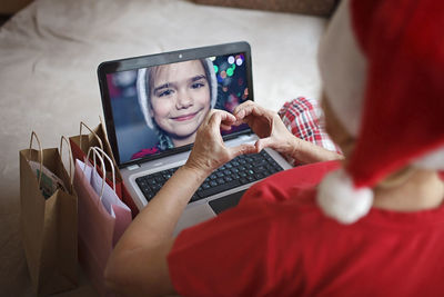 Safe online christmas celebration. senior woman in santa red hat celebrating with family virtually
