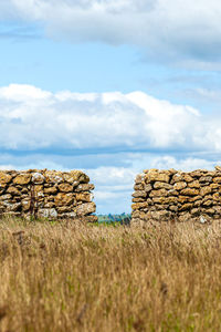 Stack of hay bales on field against sky