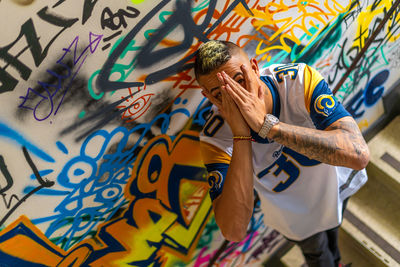 Midsection of man standing against graffiti wall