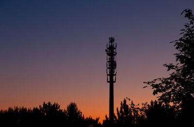 Low angle view of silhouette communications tower against sky during sunset