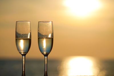 Close-up of wine glass on table against sky during sunset