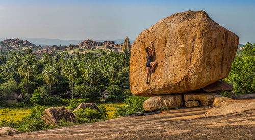 Full length of woman climbing on rock against sky