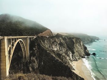 Arch bridge over mountains against sky