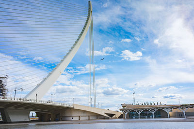 Low angle view of bridge over river against cloudy sky