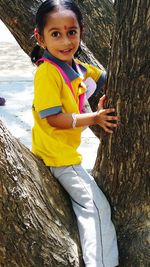 Portrait of smiling girl on tree trunk