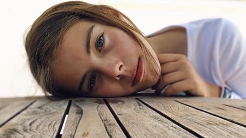 Close-up portrait of a young woman lying on wood