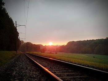 Railroad tracks against sky during sunset