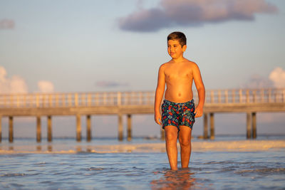 Cute kid walking on the beach at sunset