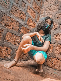 Full length of a young woman lying on wall