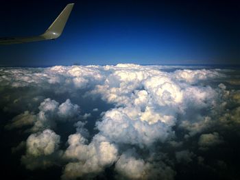 Cropped image of airplane flying over cloudscape