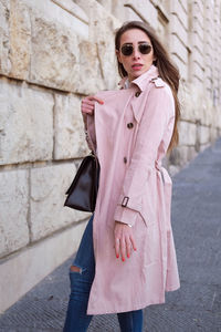 Woman wearing sunglasses standing against wall