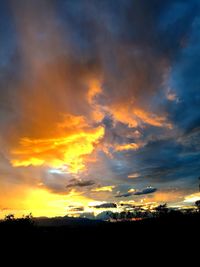 Silhouette landscape against dramatic sky during sunset