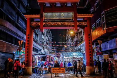 People at illuminated city street with torii gate