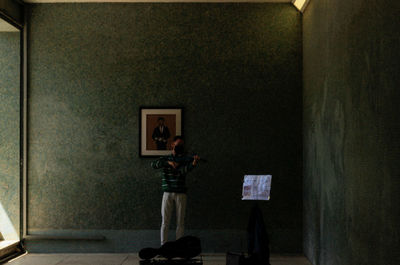 Rear view of man photographing against wall