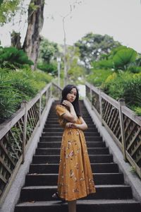 Low angle view portrait of young woman standing on staircase