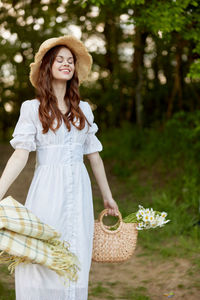 Portrait of young woman standing against trees