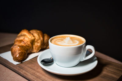 Cup, croissant and coffee on table