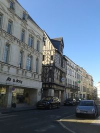 Cars on street in city against clear sky