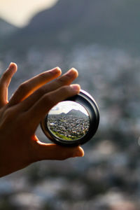 Close-up of hand holding camera against sky