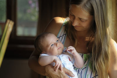 Mother carrying cute son while standing at home