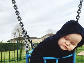 Close-up of cute baby boy sleeping on swing at park