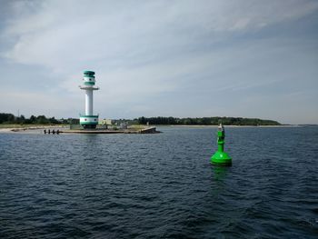 Lighthouse by sea against sky