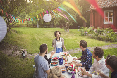 High angle view of woman talking to friends at table in garden party