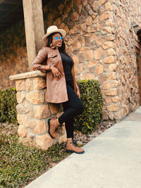 Portrait of young woman standing against wall