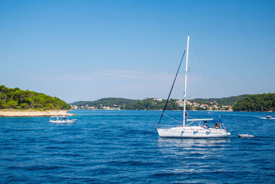 Sailboat sailing on sea against clear blue sky