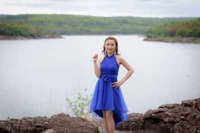 Portrait of woman standing on rock against water