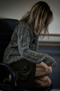 Side view of woman kneeling on chair