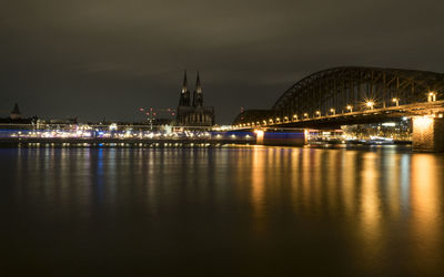 Illuminated bridge over river against sky at night