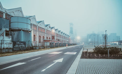 Road by buildings against sky in city