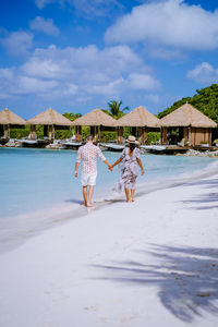 Rear view of woman walking on beach against sky