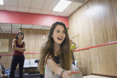 A young woman bowling with friends.