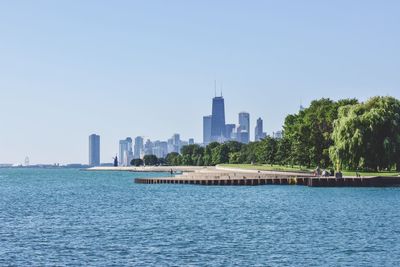 City at waterfront against clear sky