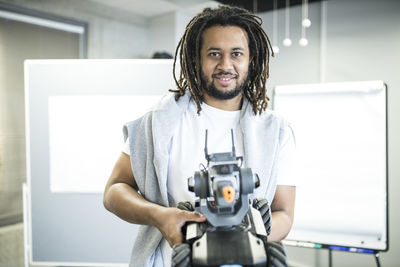 Smiling technician holding robotic combat tank at workshop