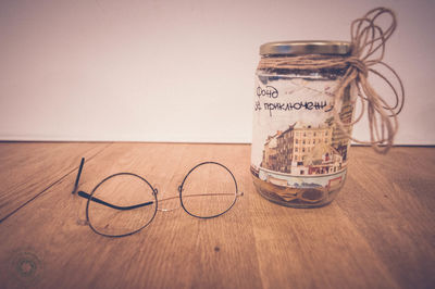 Close-up of eyeglasses by jar on wooden table