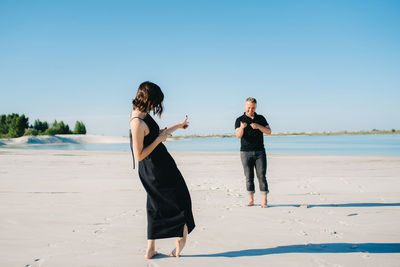 Woman standing on beach against clear blue sky