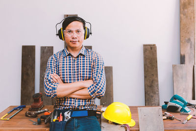 Portrait of carpenter standing with arms crossed at workshop