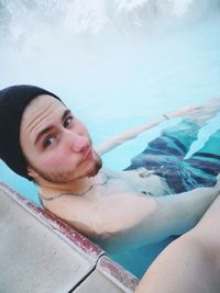 Portrait of young man by person in swimming pool