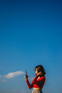 Portrait of woman standing against blue sky