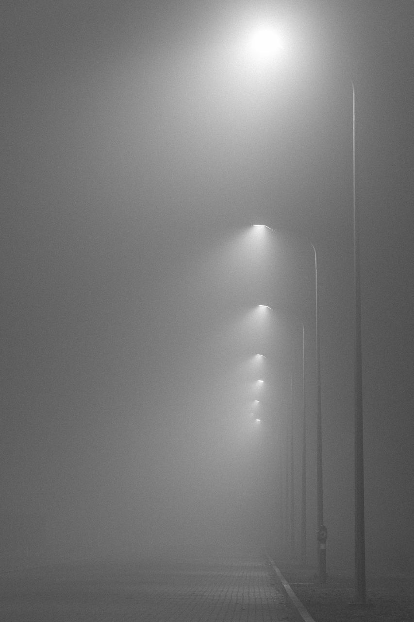 ILLUMINATED STREET LIGHT ON ROAD AGAINST SKY