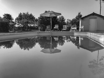 Reflection of trees and swimming pool in lake against sky