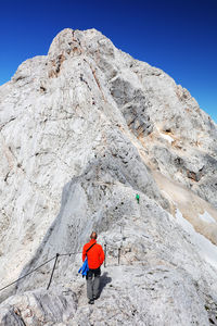 Low angle view of man climbing on mountain against clear sky