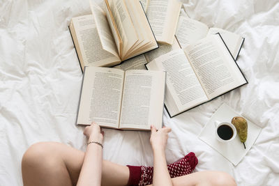 High angle view of woman reading book on bed