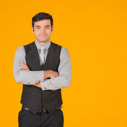Portrait of young man standing against yellow background