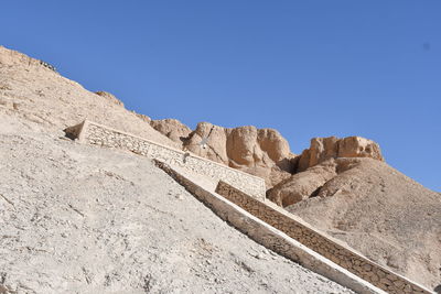 Low angle view of rocks against clear blue sky